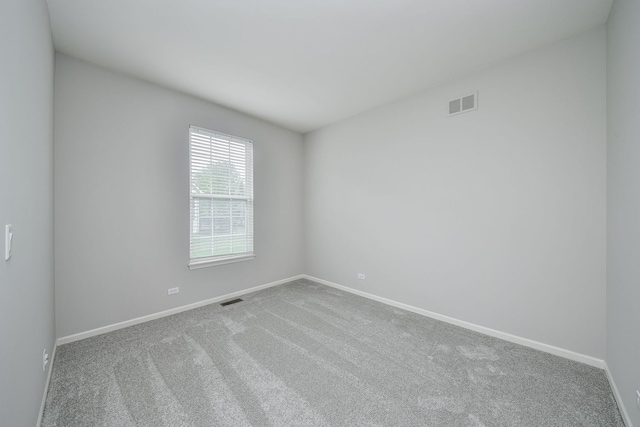 carpeted spare room featuring baseboards and visible vents