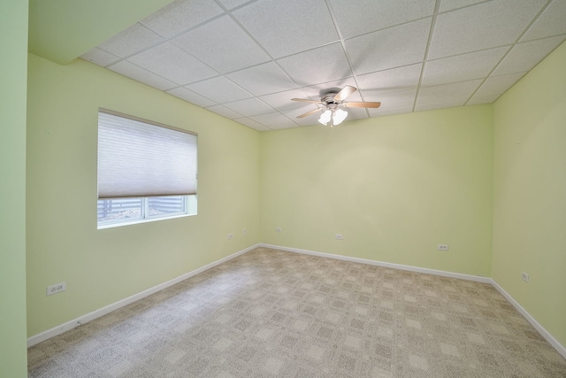 carpeted spare room with ceiling fan, a drop ceiling, and baseboards