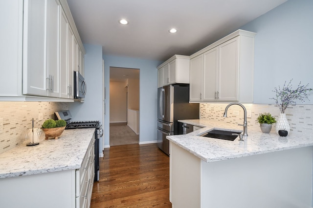 kitchen featuring a sink, appliances with stainless steel finishes, tasteful backsplash, and a peninsula