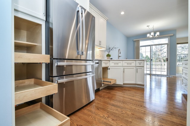 kitchen with white cabinets, stainless steel appliances, a chandelier, and a peninsula