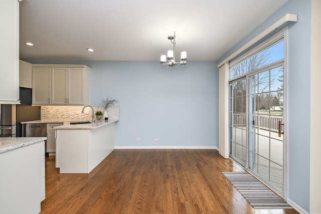 kitchen with a sink, backsplash, dark wood-type flooring, and a notable chandelier