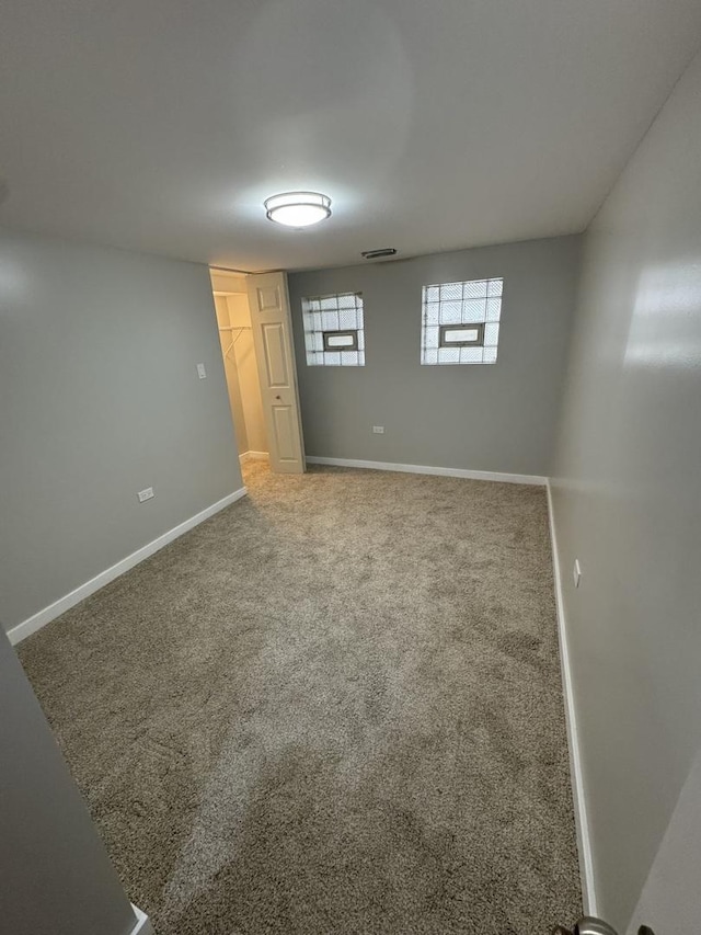 basement featuring baseboards, carpet floors, and visible vents