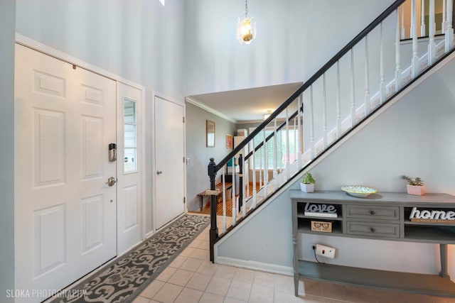 entryway with tile patterned floors, ornamental molding, and stairs