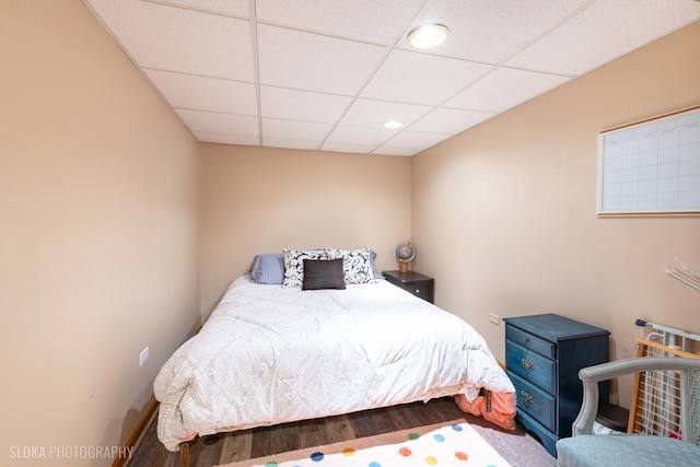 bedroom with baseboards, recessed lighting, wood finished floors, and a paneled ceiling