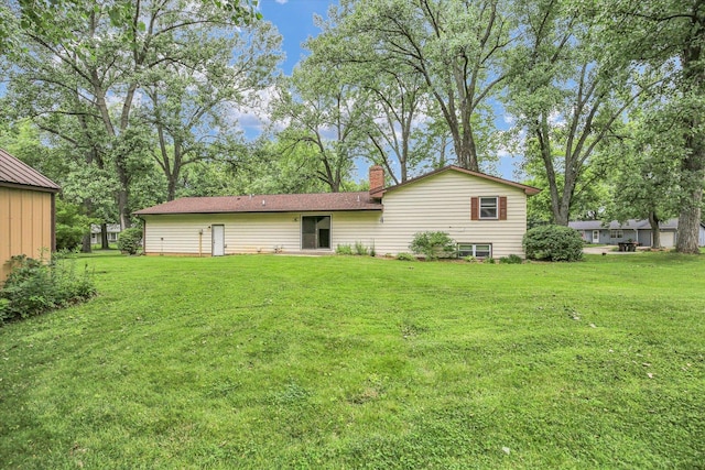 1106 Riverside Ct, Mahomet, IL 61853 - rear view of house with a lawn and a chimney