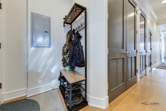 hall with light wood-style floors, baseboards, and electric panel