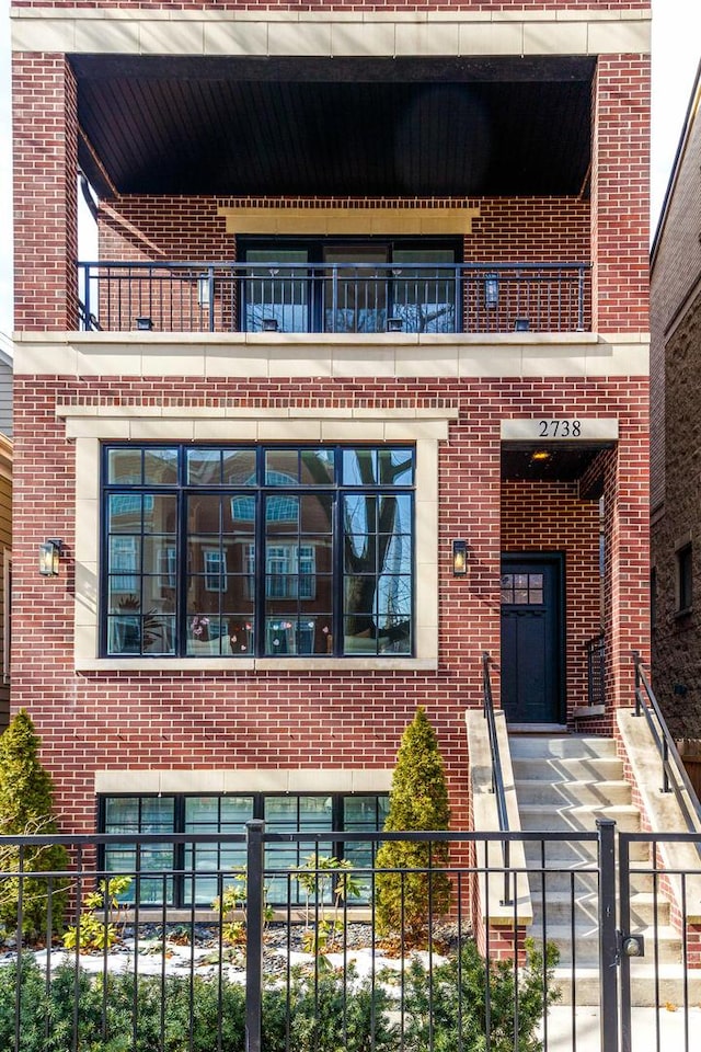exterior space featuring brick siding, fence, and a balcony