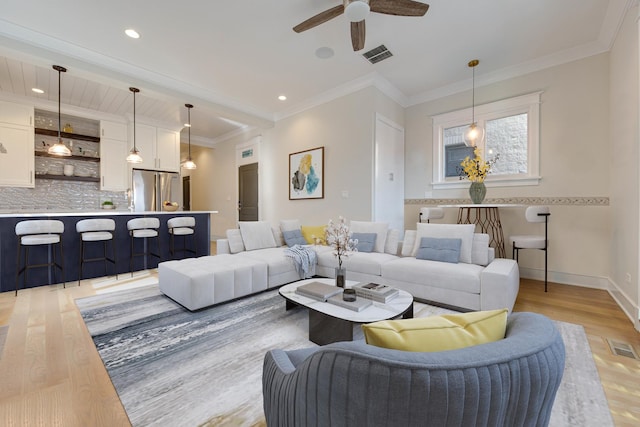 living room featuring visible vents, light wood-style floors, ceiling fan, and baseboards