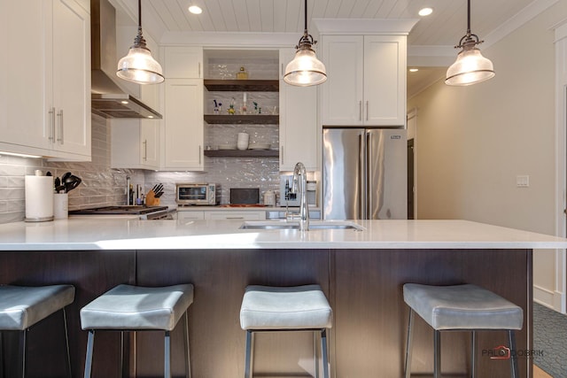 kitchen with white cabinets, open shelves, a sink, wall chimney exhaust hood, and freestanding refrigerator