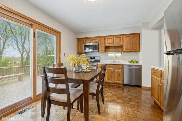 965 Sycamore Ct, Hoffman Estates, IL 60192 - kitchen with stainless steel appliances, a sink, light countertops, brown cabinetry, and baseboards