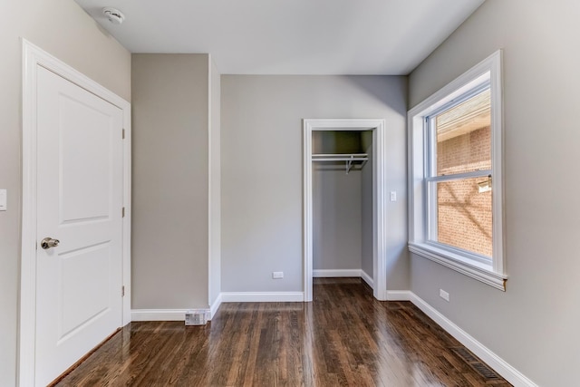 unfurnished bedroom featuring visible vents, dark wood finished floors, baseboards, and a closet