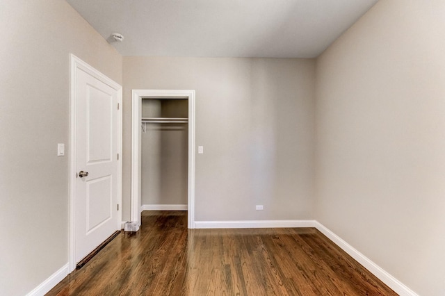 unfurnished bedroom featuring baseboards, dark wood finished floors, and a closet