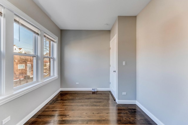 unfurnished room featuring baseboards and dark wood-style floors