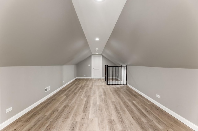 bonus room with baseboards, light wood-style floors, lofted ceiling, and visible vents