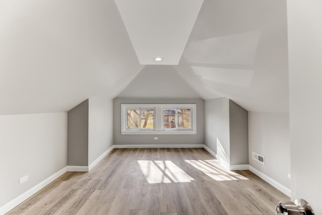 additional living space with visible vents, baseboards, wood finished floors, and vaulted ceiling