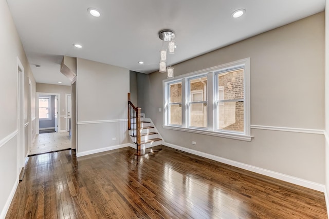 unfurnished room featuring recessed lighting, baseboards, wood-type flooring, and stairs