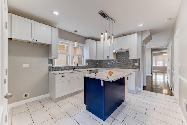 kitchen with decorative backsplash, light countertops, under cabinet range hood, white cabinetry, and a wealth of natural light