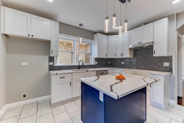 kitchen with baseboards, white cabinetry, tasteful backsplash, a sink, and hanging light fixtures