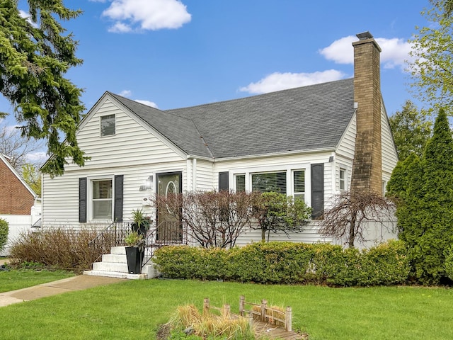 view of front of house with a front lawn, roof with shingles, and a chimney