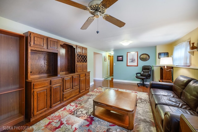 living area with ceiling fan, baseboards, and wood finished floors