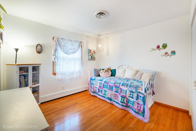 bedroom with visible vents, baseboards, wood finished floors, and baseboard heating