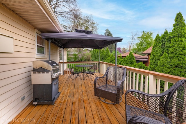 wooden deck featuring outdoor dining space, a gazebo, and grilling area