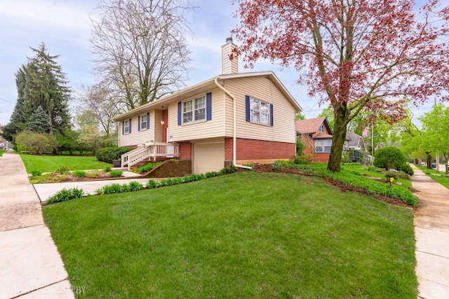 split foyer home featuring brick siding, an attached garage, a chimney, and a front yard