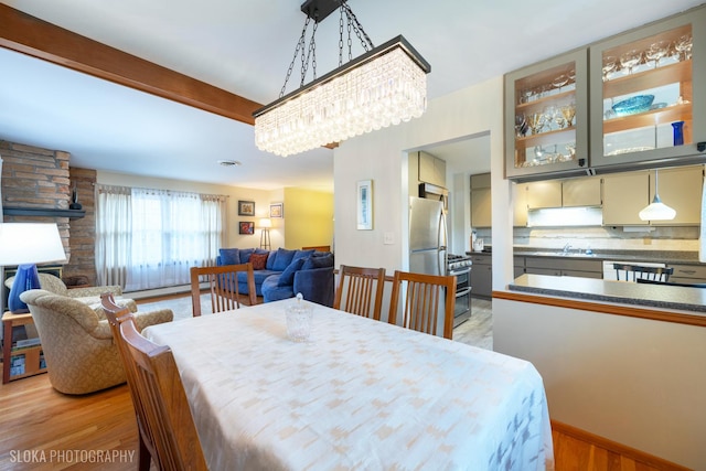 dining room featuring an inviting chandelier, light wood-style flooring, a baseboard heating unit, and a fireplace