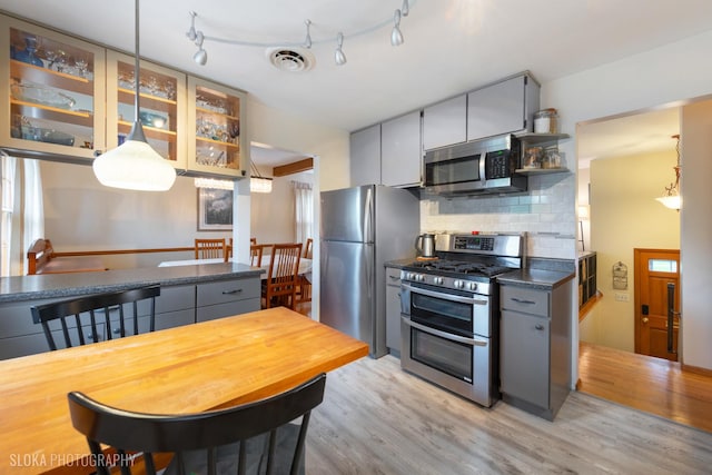 kitchen featuring open shelves, light wood-style floors, stainless steel appliances, decorative backsplash, and visible vents