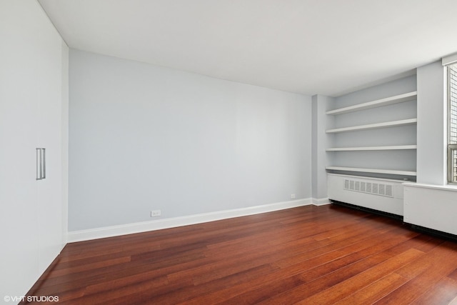 1460 N Sandburg Ter Unit 2608A, Chicago, IL 60610 - empty room featuring baseboards, built in shelves, radiator heating unit, and dark wood-type flooring