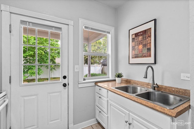 doorway to outside with a sink and baseboards