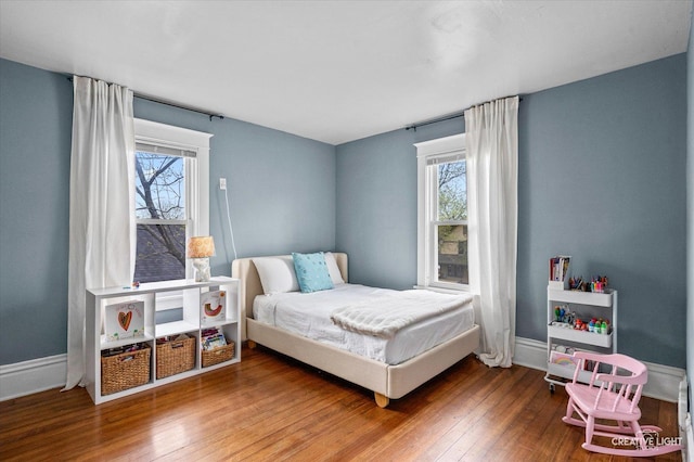 bedroom featuring baseboards, multiple windows, and hardwood / wood-style floors