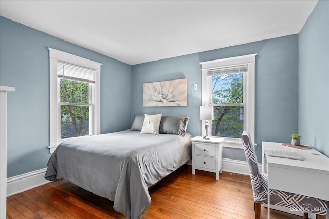 bedroom featuring baseboards, multiple windows, and hardwood / wood-style flooring