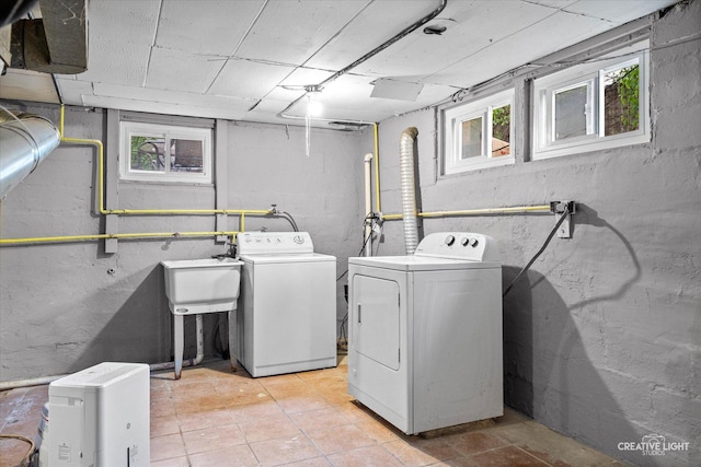 laundry area featuring light tile patterned floors, laundry area, a sink, and washer and dryer