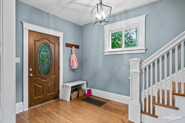 entrance foyer with visible vents, wood finished floors, baseboards, stairway, and a chandelier