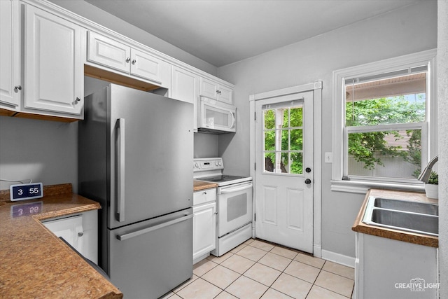 kitchen with white appliances, white cabinetry, baseboards, and light tile patterned floors