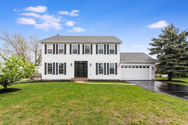 colonial inspired home with an attached garage, driveway, and a front yard