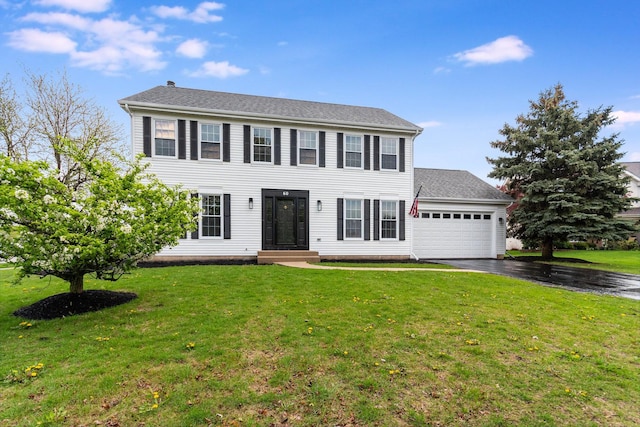 colonial house featuring a garage, driveway, and a front yard