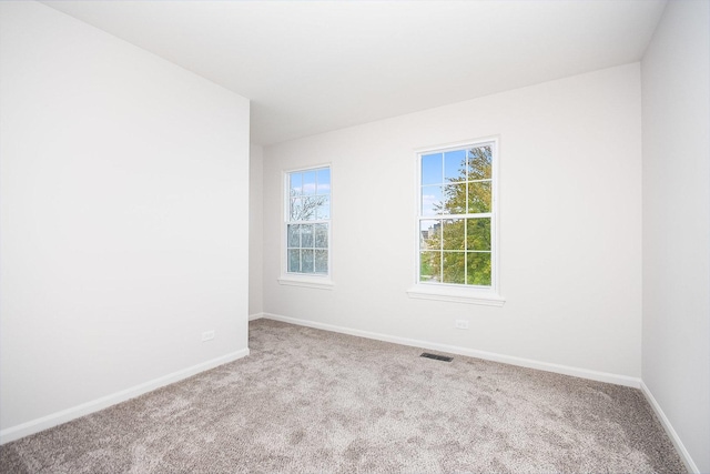 carpeted spare room featuring baseboards and visible vents