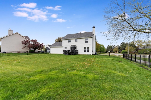 rear view of house featuring a lawn, a wooden deck, a fenced backyard, and a chimney