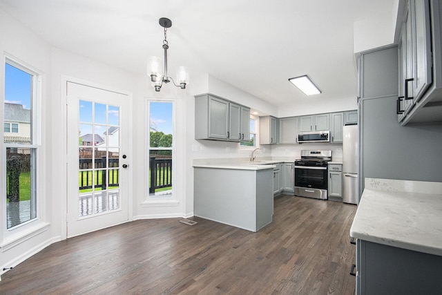 kitchen with dark wood-style flooring, a notable chandelier, appliances with stainless steel finishes, hanging light fixtures, and gray cabinets
