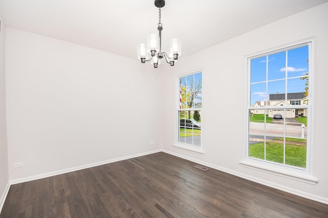 spare room featuring baseboards, visible vents, a notable chandelier, and dark wood-style floors