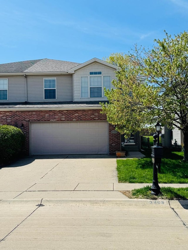 view of front of property featuring a garage, concrete driveway, and brick siding
