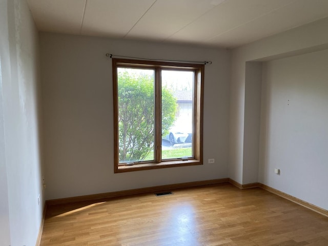 unfurnished room featuring baseboards, visible vents, and light wood finished floors