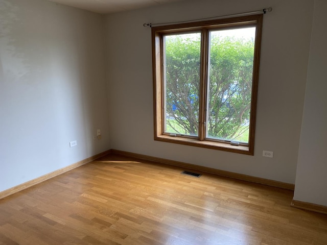 unfurnished room with baseboards, light wood finished floors, and visible vents