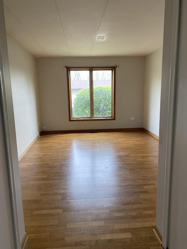 spare room featuring baseboards and wood finished floors