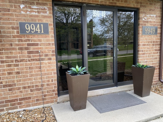 view of exterior entry featuring brick siding