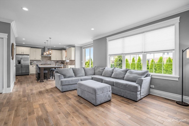 living area with an inviting chandelier, ornamental molding, and plenty of natural light