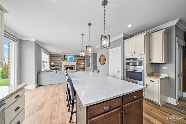 kitchen with baseboards, a fireplace, stainless steel double oven, and light wood-style flooring