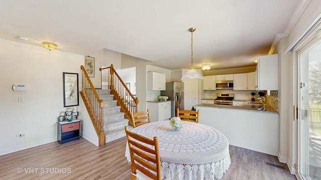 dining area with light wood-style flooring, stairway, baseboards, and ornamental molding